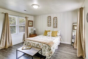 A bedroom with a bed, bedside table, and a window with curtains. - Walk to Dtwn Branson: Pet-friendly Home! (Branson)