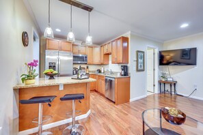 A modern kitchen with wooden cabinets, stainless steel appliances, and a bar area with stools. - Walk to Nights of Lights: Dtwn St Augustine Stay (St. Augustine)
