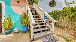 A wooden staircase leading to a door with a 'Welcome' mat, potted plants, and a fence in the background. - Walk to Nights of Lights: Dtwn St Augustine Stay (St. Augustine)