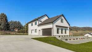 A two-story house with a garage, a well-maintained lawn, and a hilly landscape in the background. - 1 Mi to Pools: Chic Lava Hot Springs Home (Lava Hot Springs)
