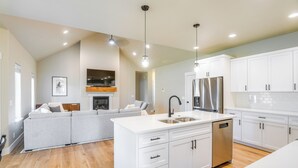A modern kitchen with white cabinetry, a stainless steel refrigerator, and a built-in dishwasher. - 1 Mi to Pools: Chic Lava Hot Springs Home (Lava Hot Springs)