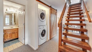 A laundry room with a washing machine and dryer, a wooden staircase, and a view of the upper floor. - Bartlett Condo: 1 Mi to Attitash Mountain Resort! (Bartlett)