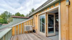 A wooden deck with a sliding glass door leading to a room with a visible bed and a staircase. - Bartlett Condo: 1 Mi to Attitash Mountain Resort! (Bartlett)
