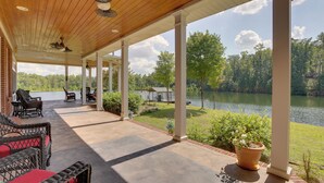 A covered patio with wicker furniture, a potted plant, and a view of a lake. - Fish, Swim & More: Lakefront Alabaster Home (Alabaster)