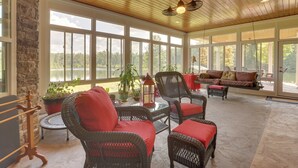 A spacious sunroom with wicker furniture, large windows, and a view of the outdoors. - Fish, Swim & More: Lakefront Alabaster Home (Alabaster)