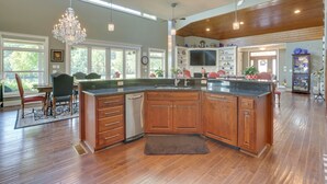 A spacious kitchen with wooden cabinets, a large island, and a chandelier. - Fish, Swim & More: Lakefront Alabaster Home (Alabaster)