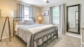 Une chambre à coucher avec un lit, un ventilateur de plafond, des lampes de chevet et un grand miroir.