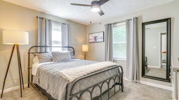 A bedroom with a bed, ceiling fan, bedside lamps, and a large mirror.
