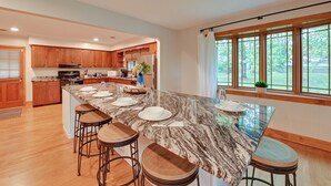 A spacious kitchen with a large island, wooden cabinets, and a view of the outdoors. - Red River Gorge Cabin: Hike + Relax! (Rogers)