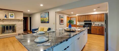 A modern kitchen with a granite island, wooden cabinets, and a built-in oven.