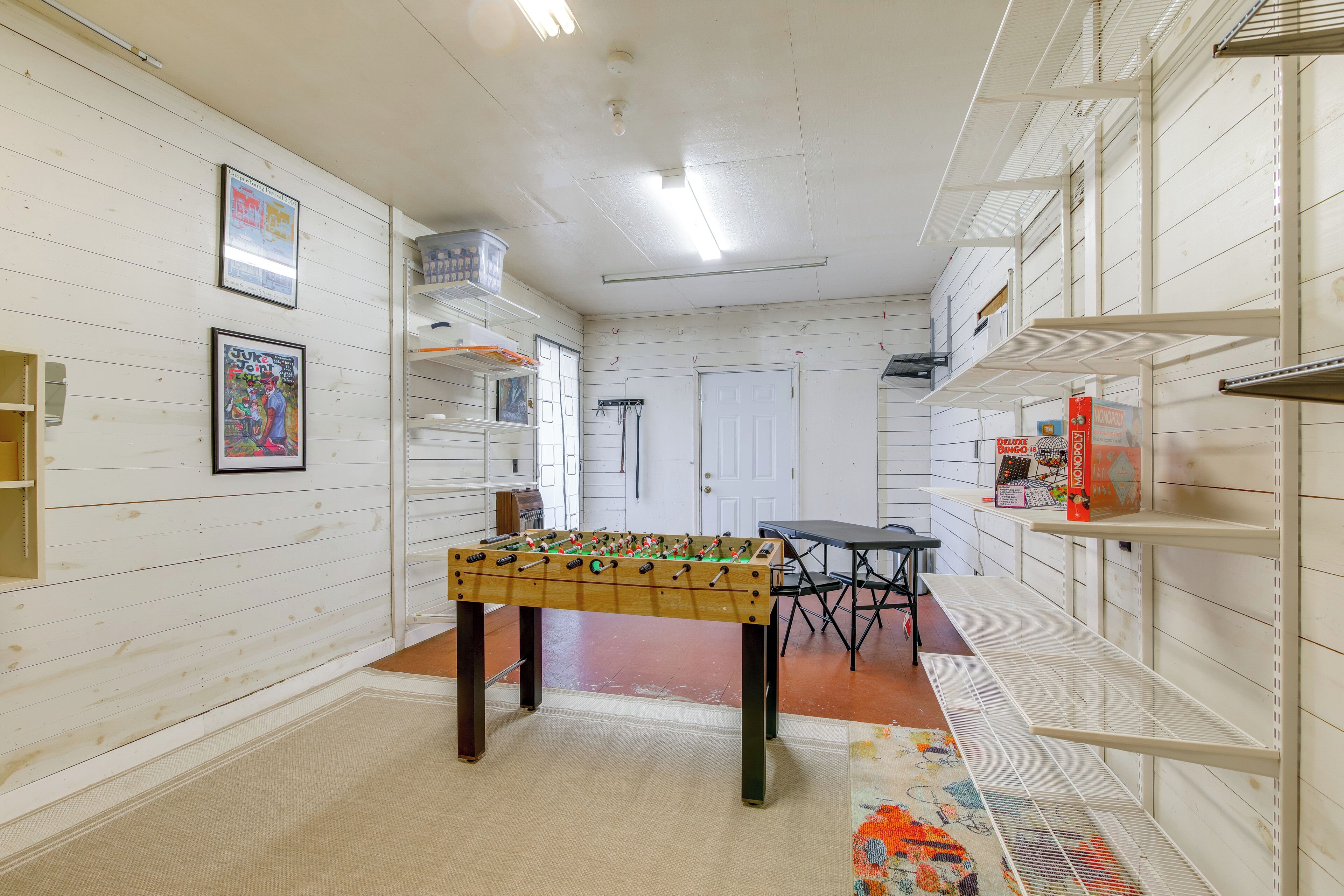 Une pièce avec un baby-foot, une porte et une table avec des chaises.