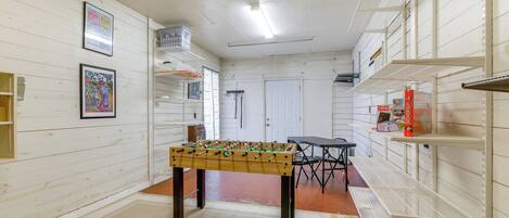 A room with a foosball table, a door, and a table with chairs.