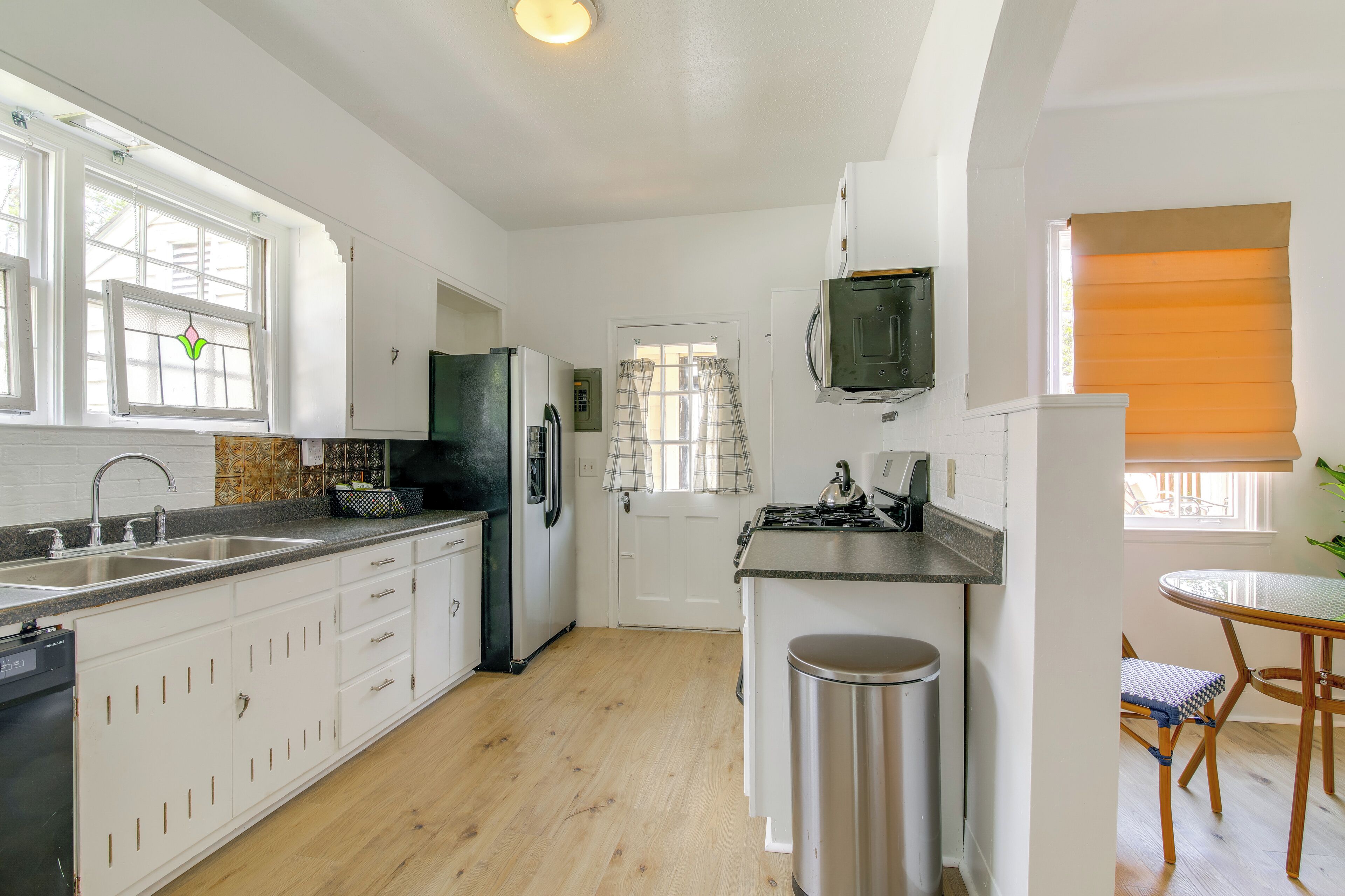 A modern kitchen with white cabinets, a stainless steel sink, and a built-in oven.