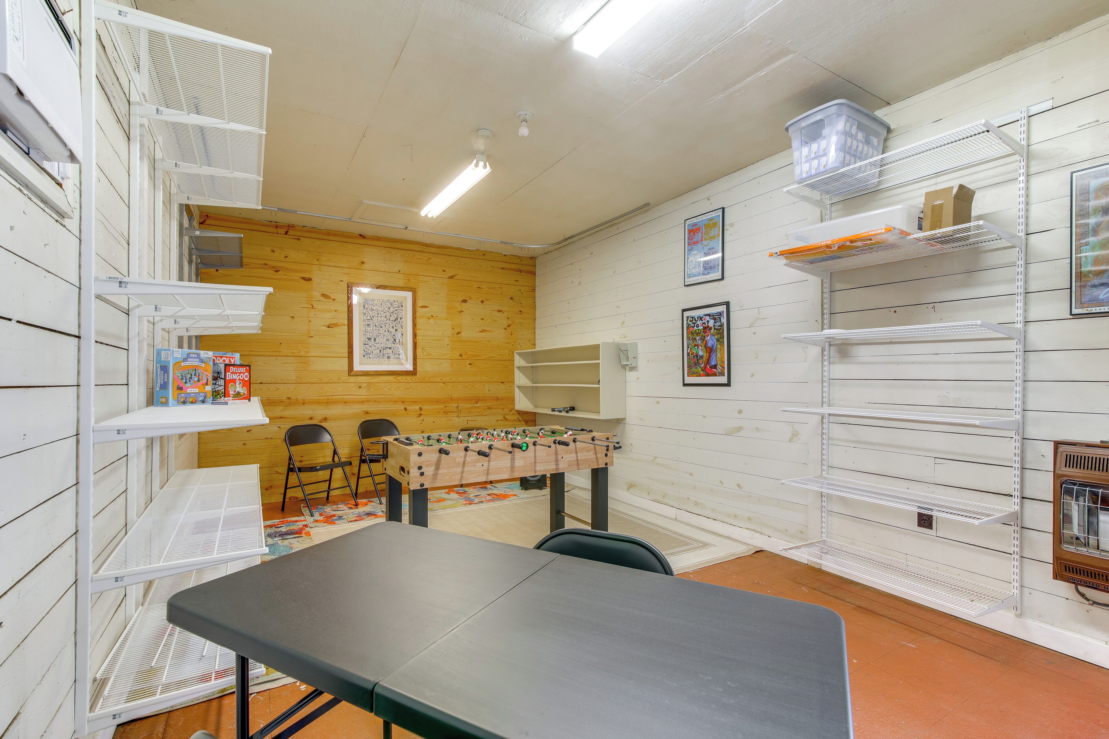 A room with white shelving units, a foosball table, and a table with chairs.