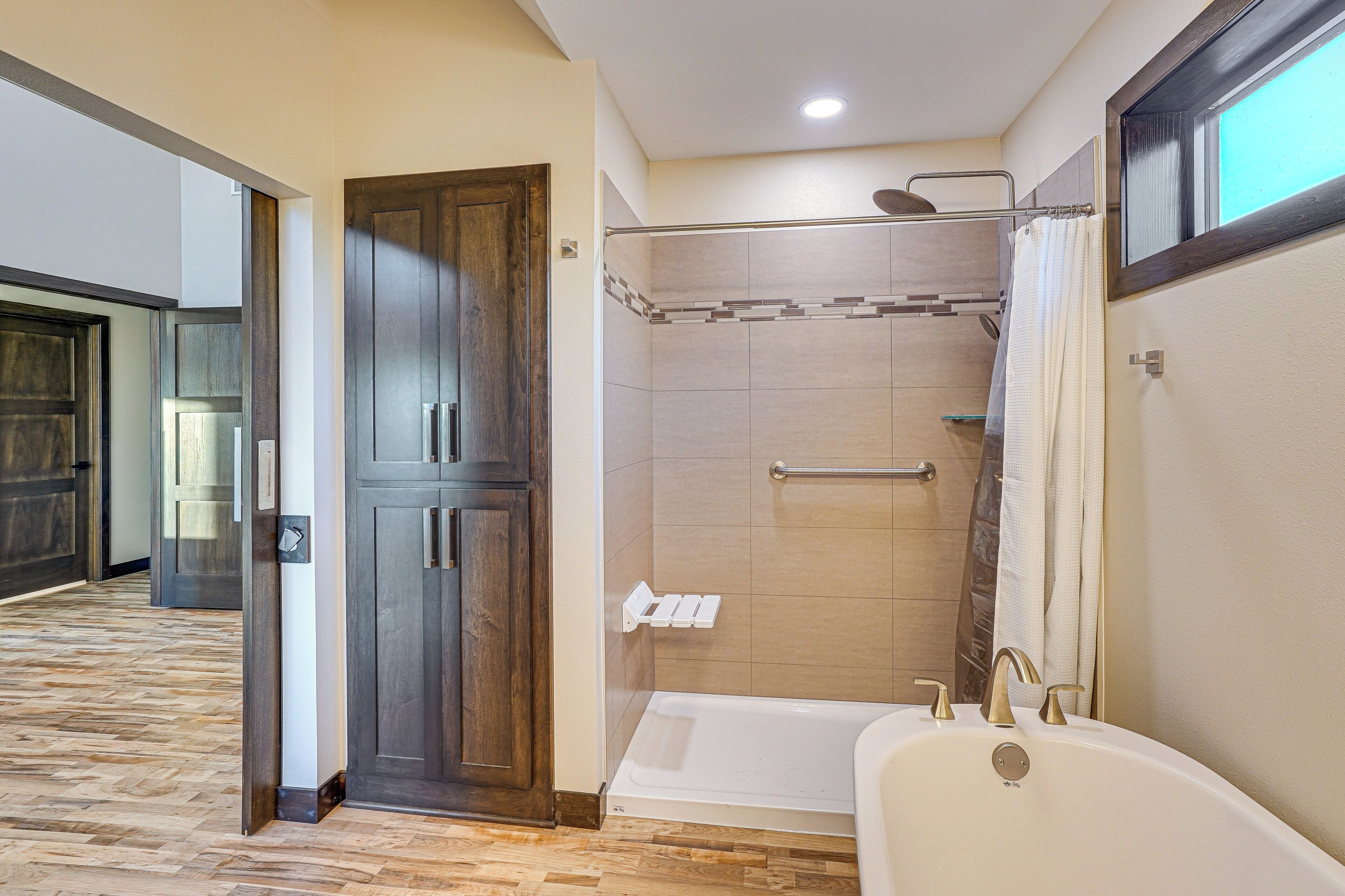 Un baño con bañera, ducha y puerta de madera.