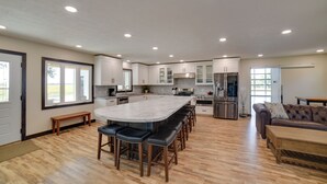 Una cocina amplia con una isla grande, piso de madera y electrodomésticos modernos.