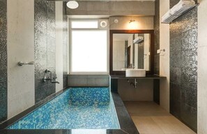 A bathroom with a blue-tiled shower, a sink, and a mirror. - Deep International Goa (Mandrem)