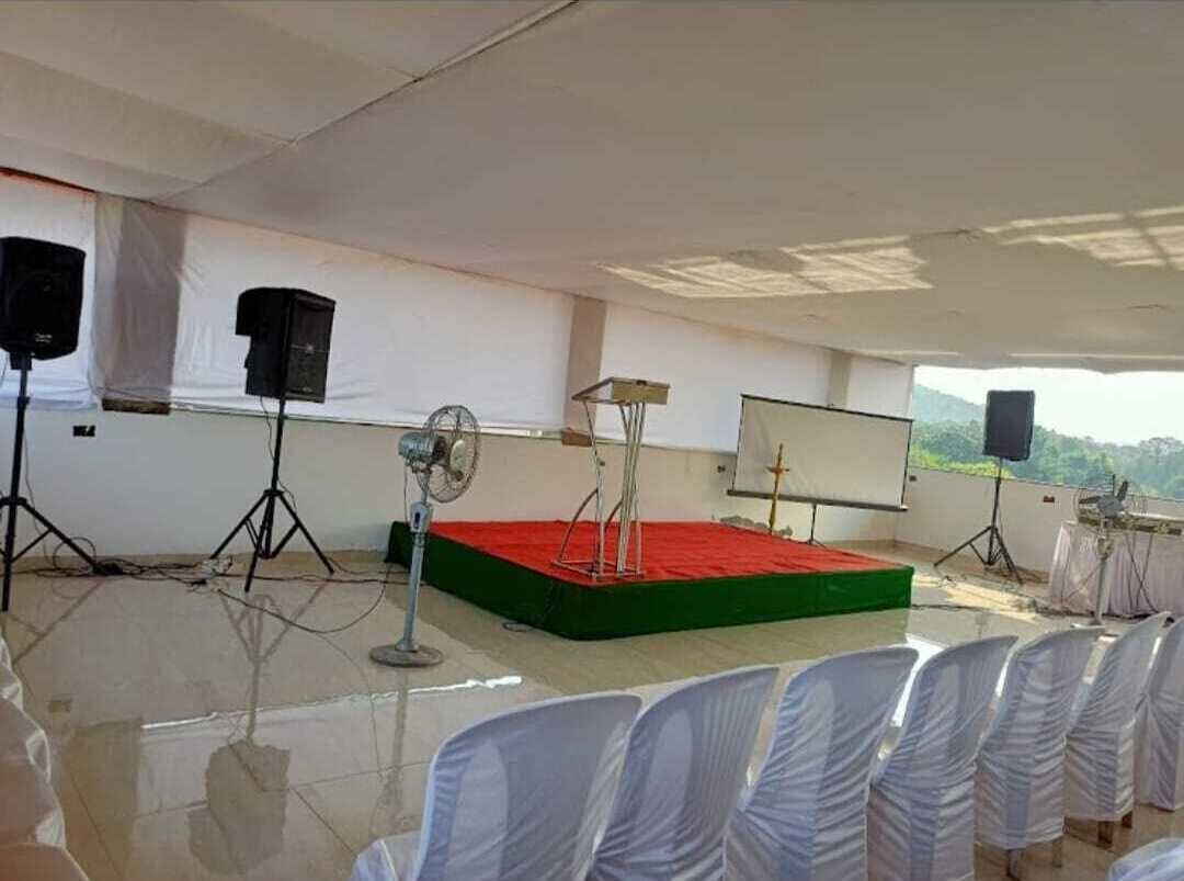 A conference room with a stage, white chairs, and a projector screen.