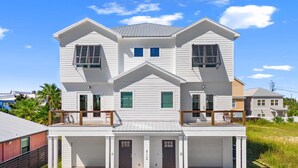 A two-story house with a covered front porch, a garage, and a balcony. - 3BD/3BA Newly Built Home, Steps from Beach, Private Pool + Game Room (Panama City Beach)