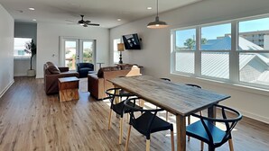 A spacious living area with a wooden dining table, black chairs, a sofa, and a ceiling fan. - 3BD/3BA Newly Built Home, Steps from Beach, Private Pool + Game Room (Panama City Beach)