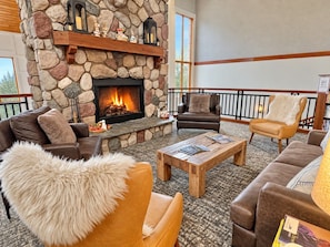 A cozy lobby with a stone fireplace, leather sofas, and a wooden coffee table.