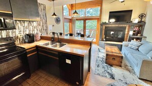 Una cucina moderna con piano cottura integrato, lavello e zona pranzo con tavolo e sedie in legno.