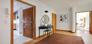 A hallway with a wooden door, a black console table with a mirror, and a framed picture on the wall.