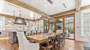 A spacious kitchen with wooden beams, a large island, and a dining area with chairs. - Tranquility|Private Community Beach Access|Pool|Golf Cart|Game Room (WaterSound)