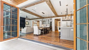 An open-plan living and dining area with a wooden ceiling, a fireplace, and a kitchen with white cabinets and a stainless steel range hood. - Tranquility|Private Community Beach Access|Pool|Golf Cart|Game Room (WaterSound)