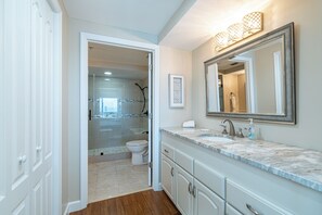 A modern bathroom with a marble countertop, a large mirror, and a glass shower enclosure. - Beachfront 2br/2ba condo on the 10th floor with free beach chairs included! (Panama City Beach)