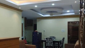 A spacious living area with a marble floor, a wooden reception desk, and a dining table with patterned chairs. - Haven Garden Homestay (Port Blair)