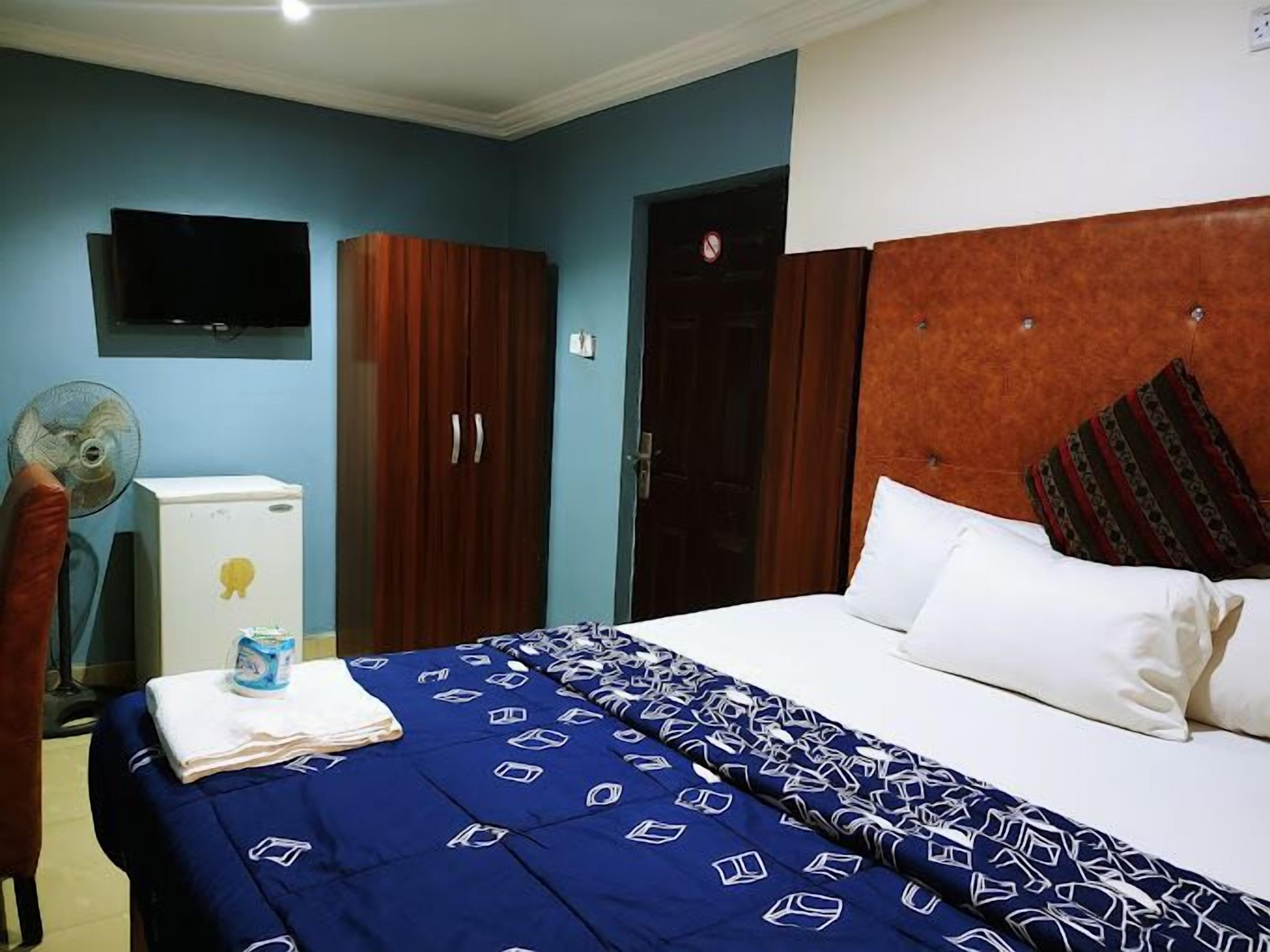 Een hotelkamer met een bed, een kledingkast, een televisie en een ventilator.
