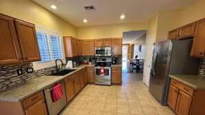 A kitchen with wooden cabinets, a granite countertop, a stainless steel refrigerator, and a built-in oven. - Charming 3-bedroom house in Gold Canyon with 1 gigabit WiFi and amazing views (Gold Canyon)