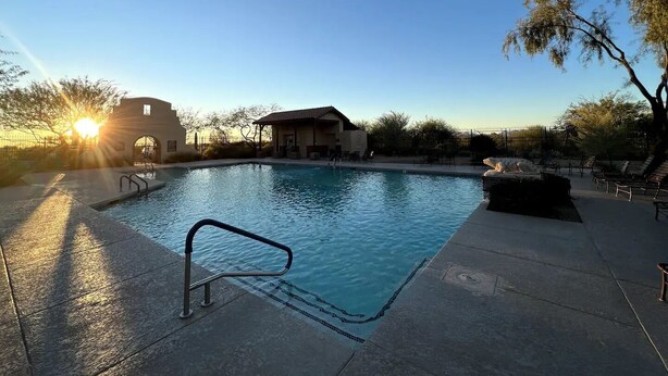 A swimming pool with a sunlit sky, a building in the background, and a tree to the right. - Charming 3-bedroom house in Gold Canyon with 1 gigabit WiFi and amazing views (Gold Canyon)