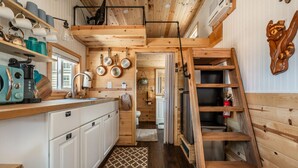 A compact kitchen with white cabinets, a sink, and a wooden ladder. - Glamping Under the Stars | Firepit, BBQ & Views (Woodland Park)