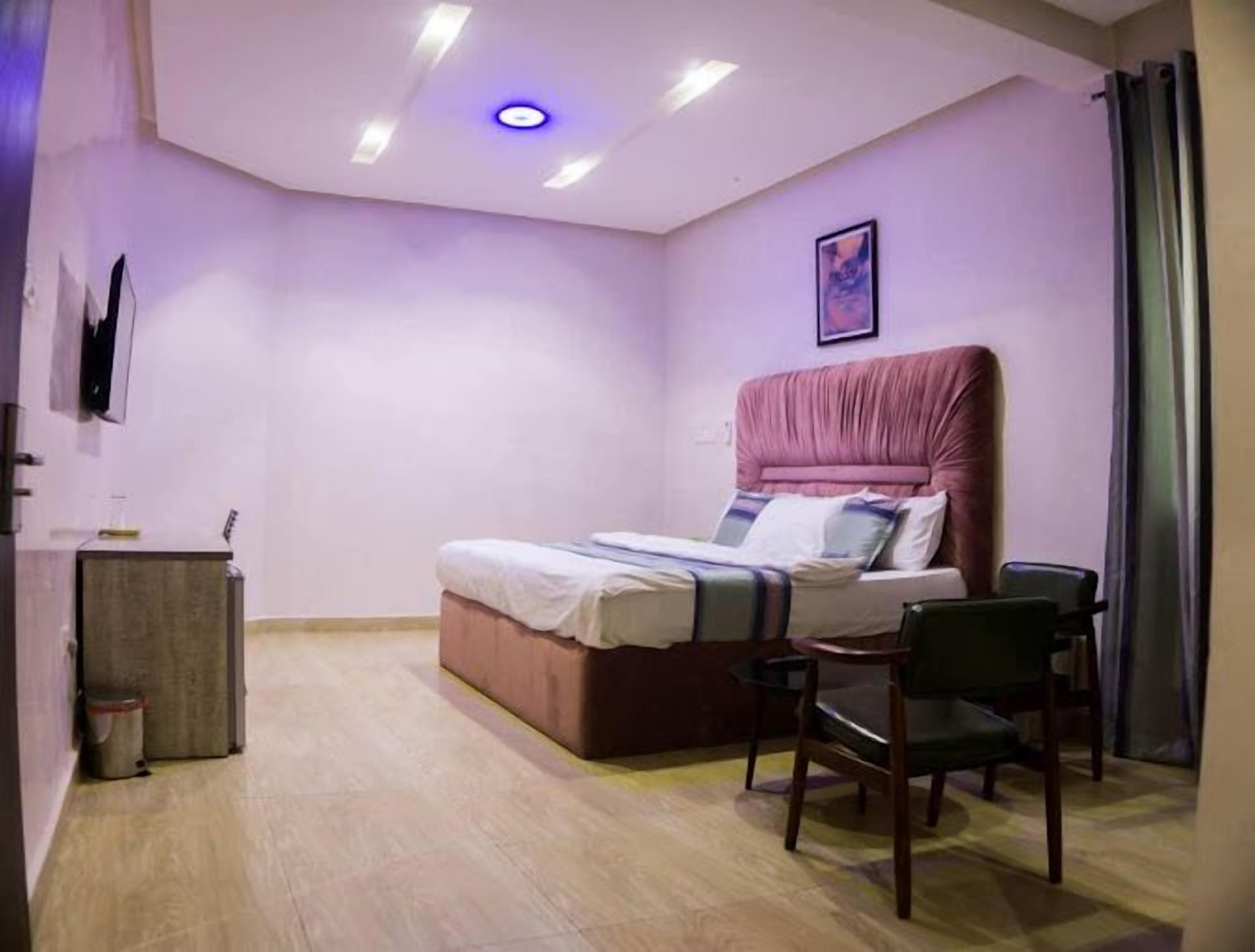 A bedroom with a bed, a desk, and a chair.