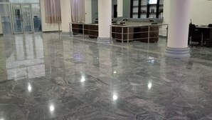 Un vestíbulo espacioso con suelo de mármol pulido, una mesa de recepción y una columna grande.