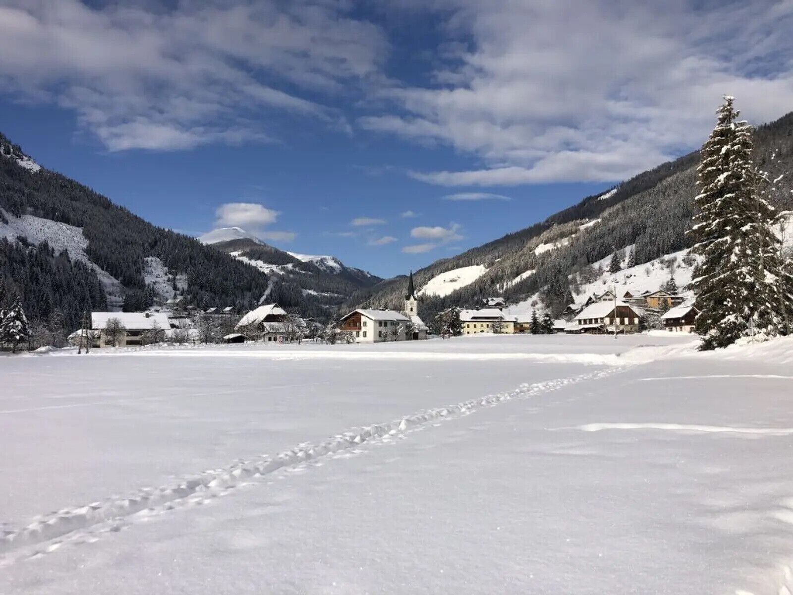 A snow-covered landscape with a clear sky, a church, and several buildings.