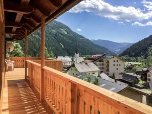 A wooden balcony with a view of a mountain village and a church. - Felsenhütte by Globalimmoservice (Ebene Reichenau)