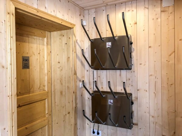 A wooden cabin with two metal racks mounted on the wall, each with multiple hooks. - Felsenhütte by Globalimmoservice (Ebene Reichenau)