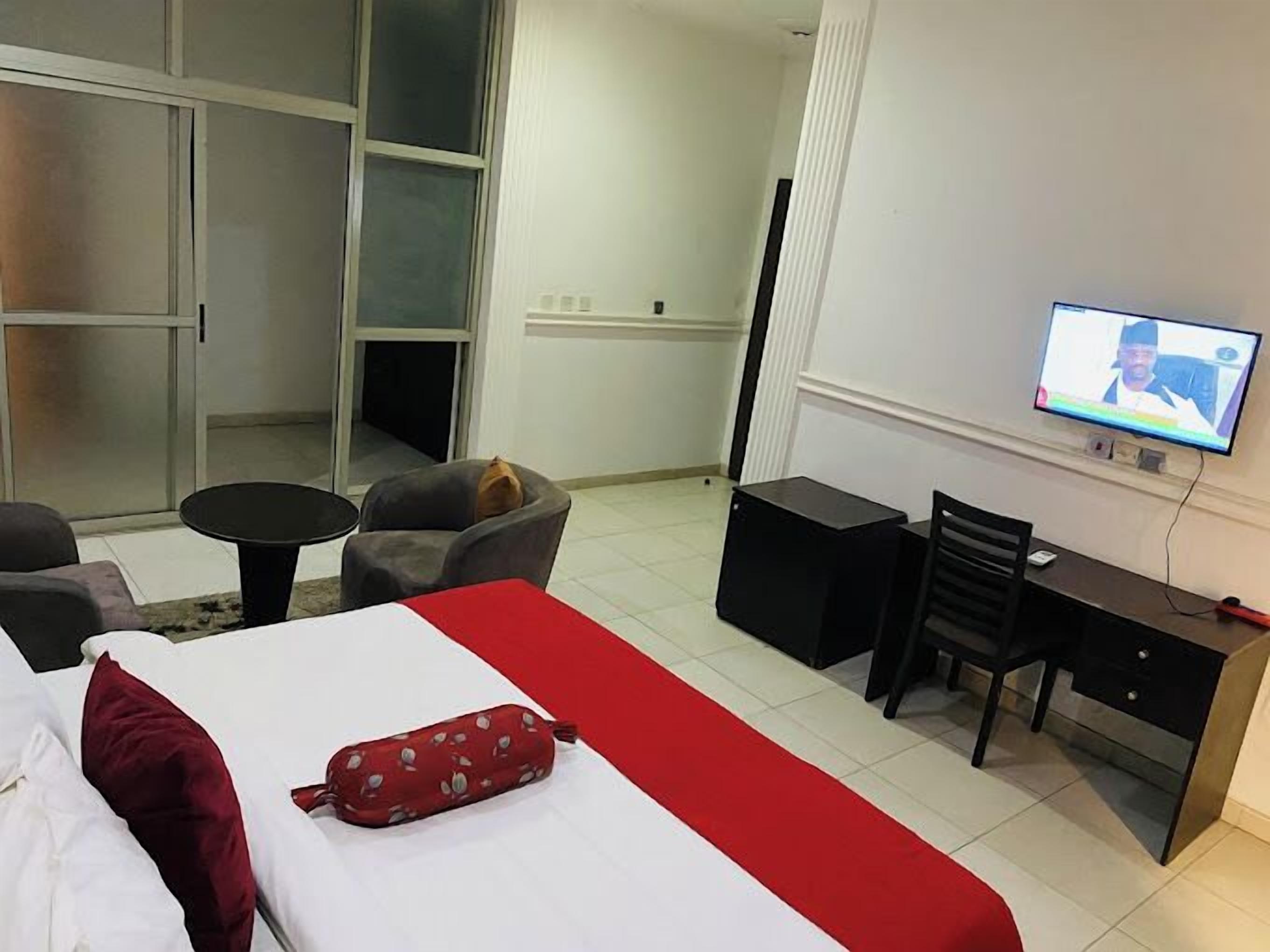 A hotel room with a bed, a desk, a chair, a television, and a sofa.