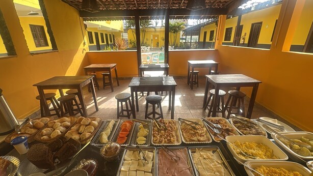 A buffet area with various food items and tables and chairs arranged for dining. - Pousada Vila do Sol (Ipojuca)