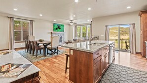 A spacious kitchen with a central island, dining area, and a view of a hilly landscape.