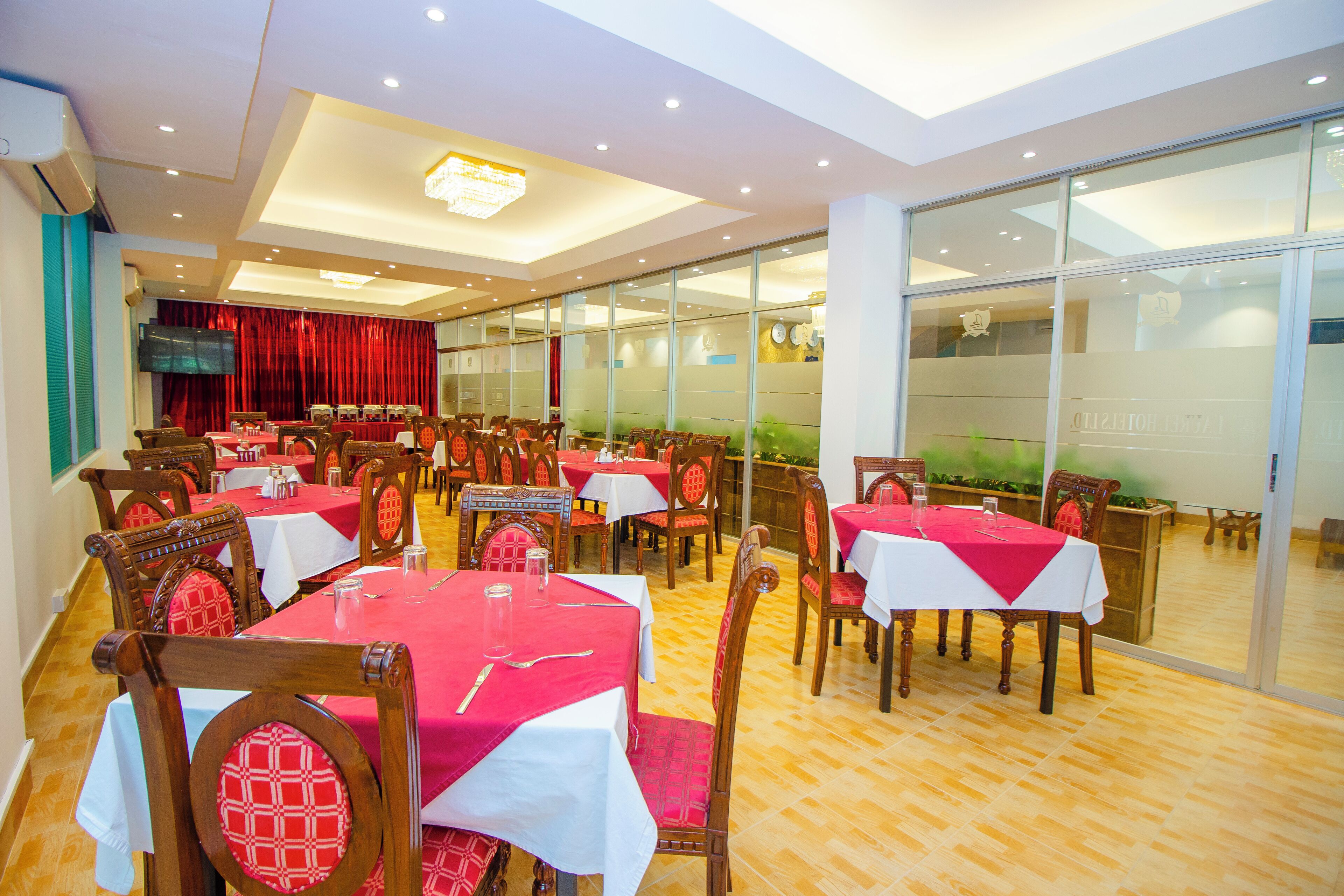 A dining area with multiple tables, chairs, and a television screen.