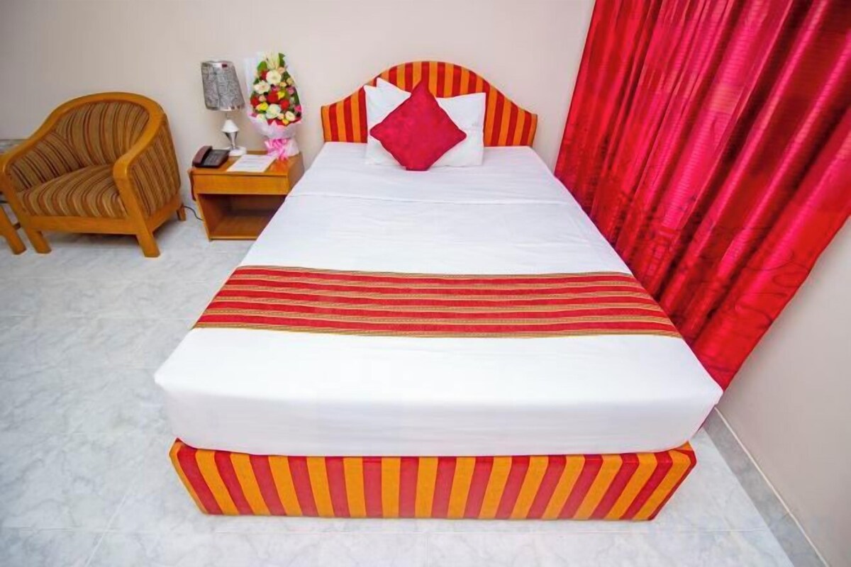 A bed with a striped bedspread, a nightstand with a lamp, and a chair.