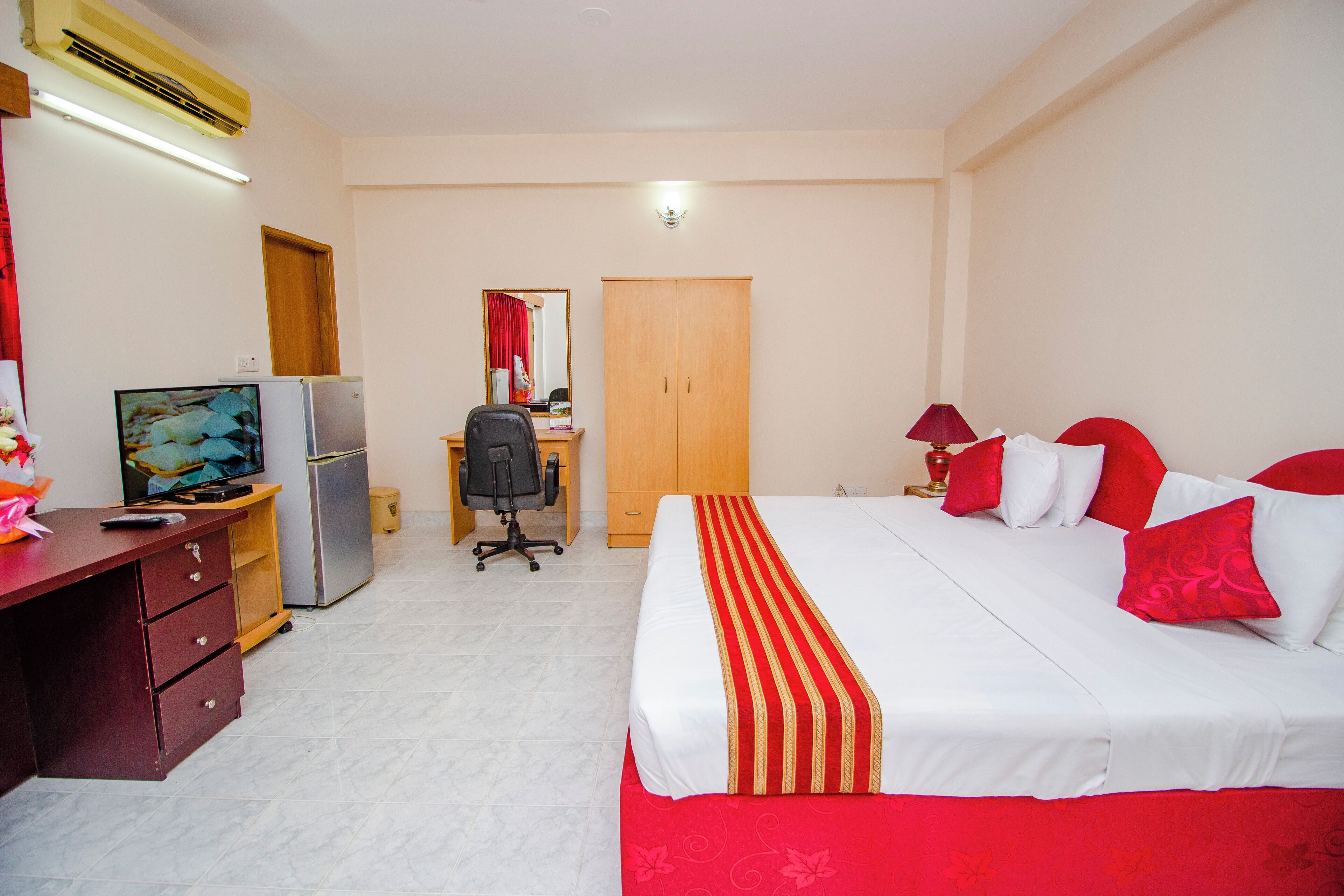 A hotel room with a bed, desk, chair, wardrobe, and a television.