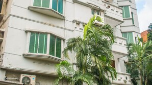 Ein mehrstöckiges Gebäude mit Balkonen, Klimaanlagen und einem geschlossenem Eingangsbereich.
