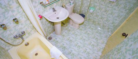 A bathroom with a bathtub, sink, toilet, and a mirror.