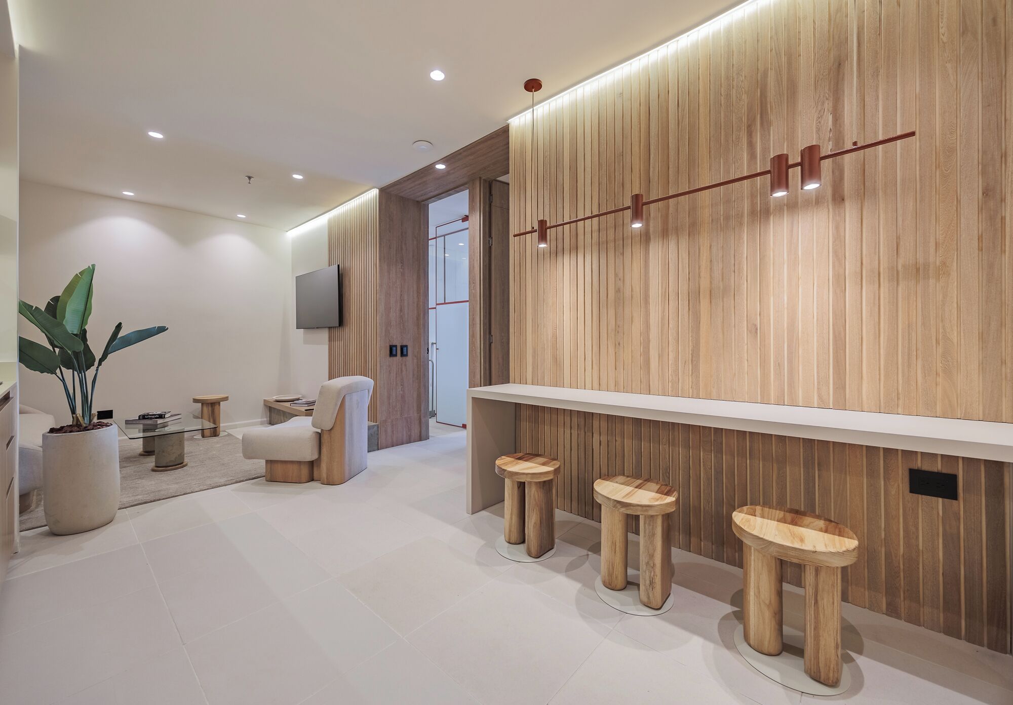A modern interior with a wooden accent wall, a flat-screen TV, and a seating area with stools.