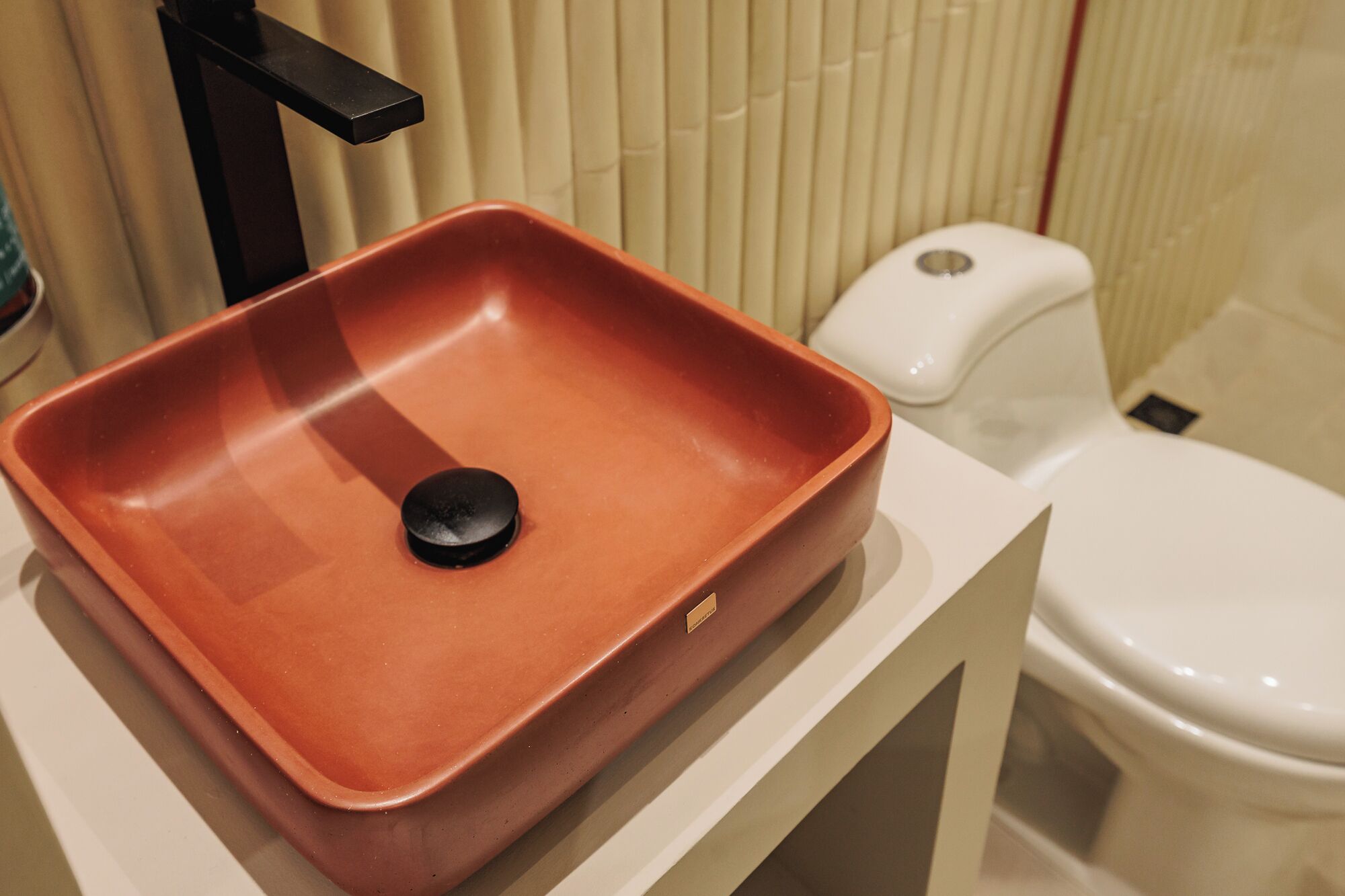 A bathroom with a terracotta sink, a black faucet, and a white toilet.